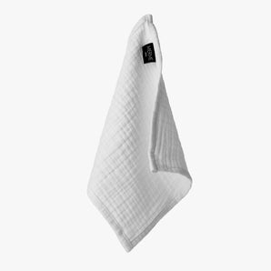 Ein Set von vier weißen, strukturierten Musselin-Gesichtsreinigungstüchern aus natürlicher Baumwolle von MERME Berlin hängt mit einem schwarzen Etikett auf einem schlichten weißen Hintergrund.