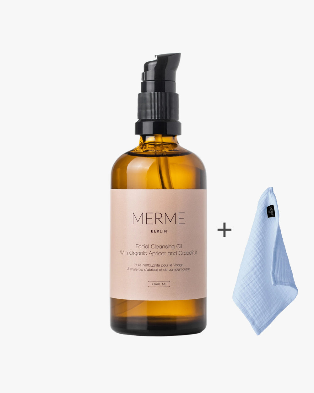 Bernsteinfarbene Flasche MERME Berlin FACIAL CLEANSING OIL mit Grapefruit und schwarzem Pumpspender, präsentiert neben einem gefalteten hellblauen Reinigungstuch auf schlichtem weißem Hintergrund.
