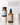 Zwei Flaschen des MERME Berlin FACIAL CLEANSING OIL mit Grapefruit, eine mit schwarzem Deckel und eine mit Pumpe, stehen auf weißen Marmorständern. Ein deutscher Text erklärt, wie sie die doppelte Reinigung für eine tiefere Hautreinigung unterstützen.