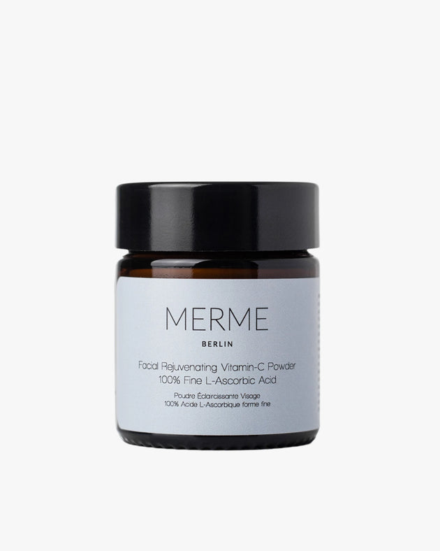 Auf einem schlichten weißen Hintergrund ist ein braunes Glasgefäß mit schwarzem Deckel und der Aufschrift „MERME Berlin FACIAL REJUVENATING VITAMIN C POWDER“ zu sehen.