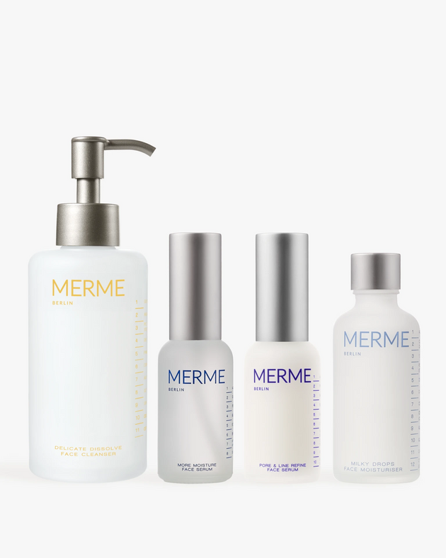 Vier minimalistische weiß-silberne Flakons aus dem "HYDRATE BY DAY, CLARIFY BY NIGHT"-Set von MERME Berlin - Gel-Reiniger, Feuchtigkeitsserum, Sprüh-/Tropfflasche und Feuchtigkeitscreme - sind nebeneinander angeordnet.