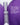 Eine silber-violette Flasche des PORE & LINE REFINE FACE SERUM von MERME Berlin steht zwischen violetten Formen. Der deutsche Text hebt Bakuchiol und Niacinamid als sanfte Retinol-Alternativen hervor, die die Kollagenproduktion ankurbeln, Hyperpigmentierung reduzieren und feine Linien glätten.