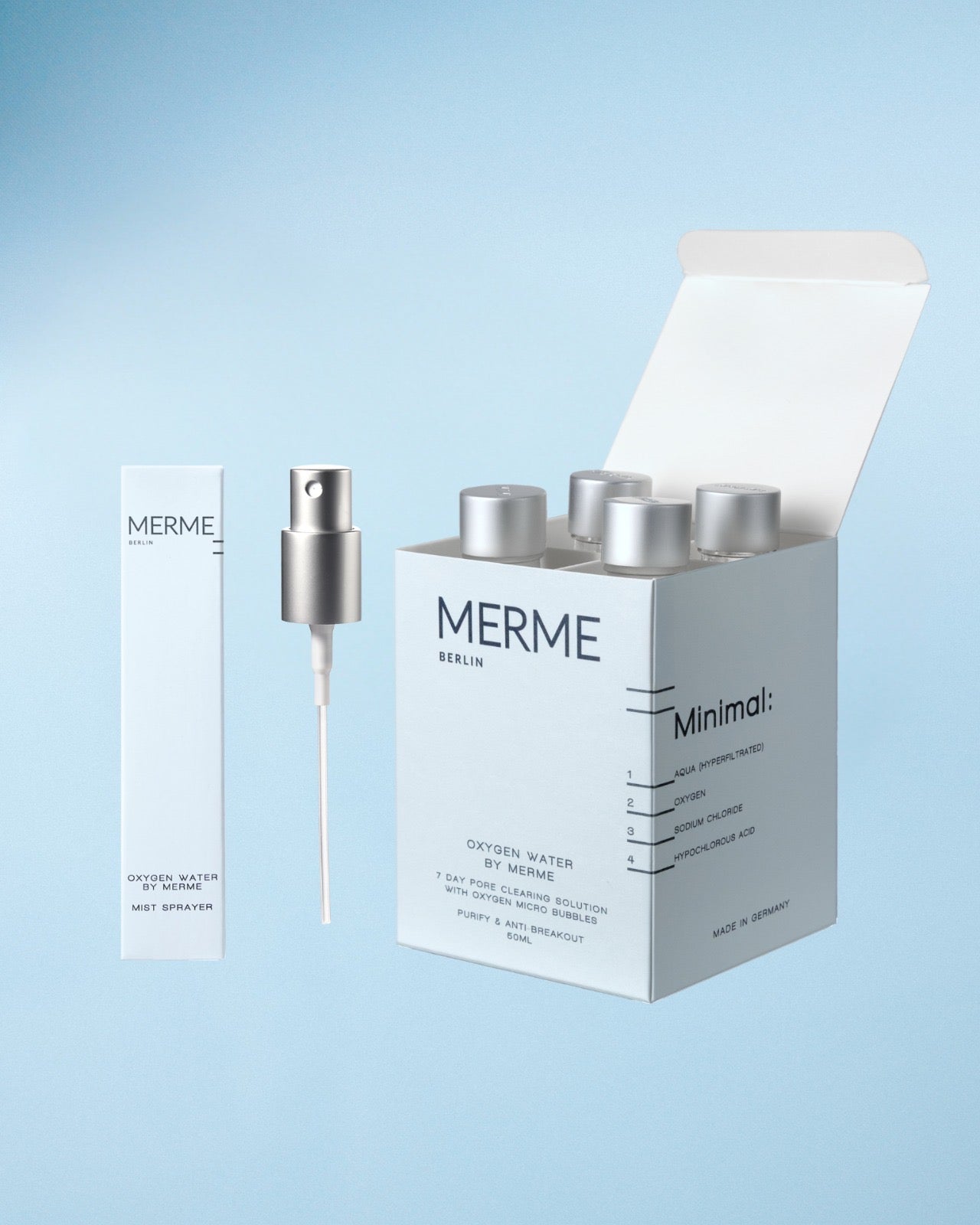Eine weiße "MERME Berlin"-Schachtel hält Flaschen mit silbernen Verschlüssen. Daneben suggerieren die schlanke Dose OXYGEN WATER BY MERME 4-WOCHEN-SET und eine silberne Sprühdüse fortschrittliche Sauerstoff-Microbubble-Technologie auf hellblauem Hintergrund.