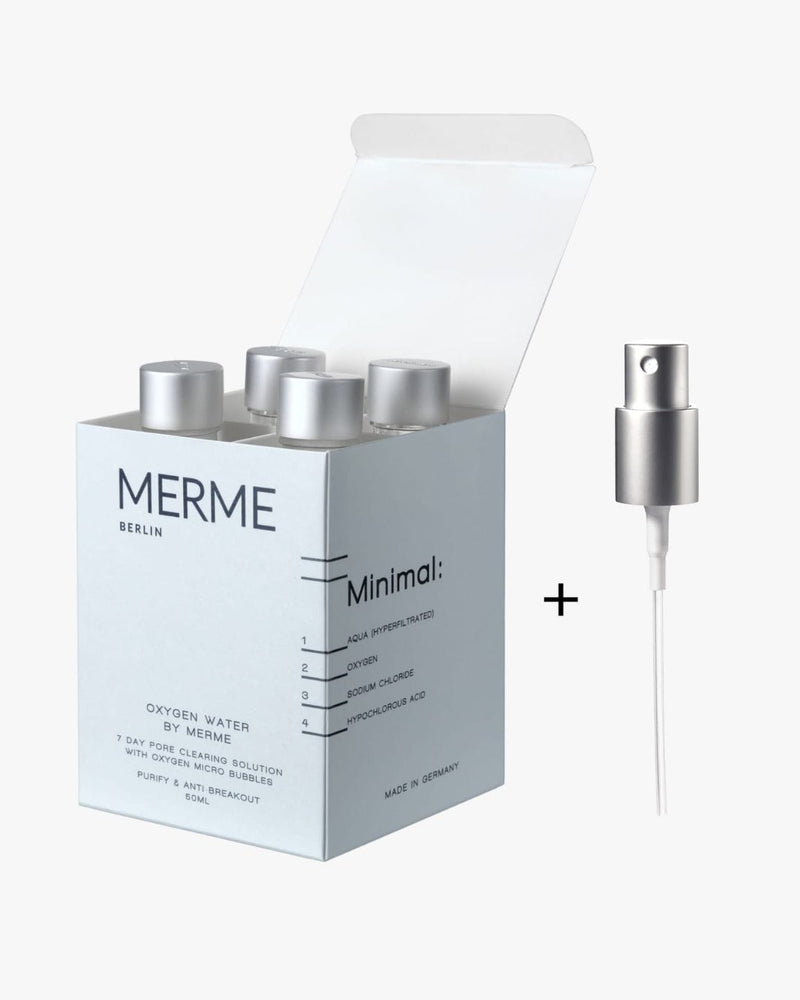Eine Schachtel mit der Aufschrift "MERME Berlin Oxygen Water Pore Clearing Solution (8 Wochen)" enthält vier Flaschen mit Silberverschluss. Daneben befindet sich eine silberne Sprühpumpe mit weißem Schlauch, die Sauerstoff-Microbubble-Technologie für empfindliche Haut verwendet.