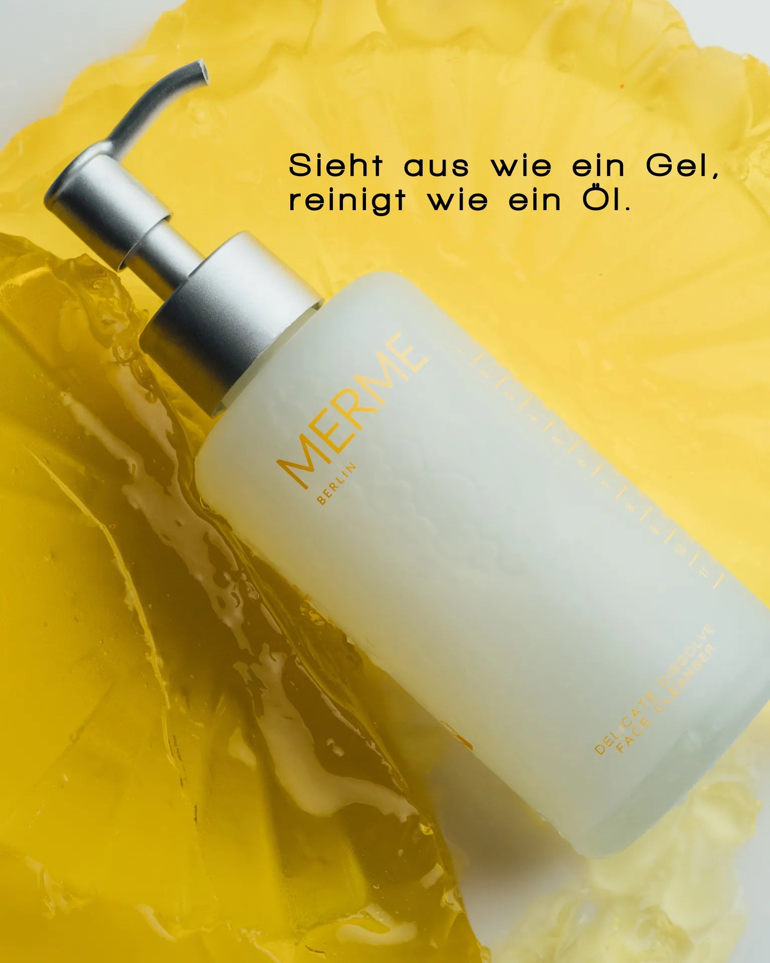 Eine Flasche MERME Berlin DELICATE DISSOLVE FACE CLEANSER mit einem Pumpspender ruht auf einer gelartigen Oberfläche. Der deutsche Text darüber lautet: "Sieht aus wie ein Gel, reinigt wie ein Öl - sanfte Reinigung für empfindliche Haut.