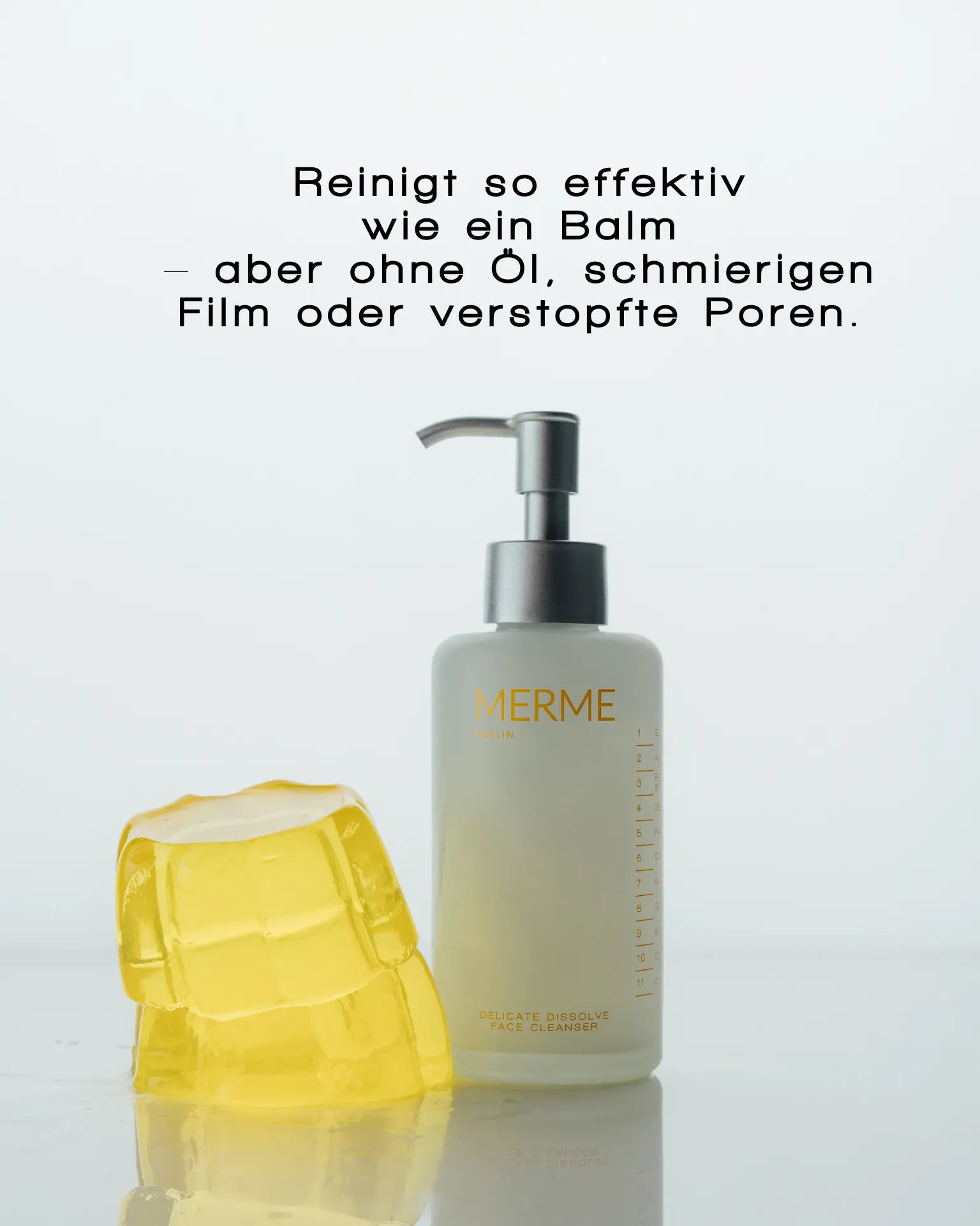 Eine Flasche MERME Berlin DELICATE DISSOLVE FACE CLEANSER mit einer Pumpe steht neben einem gelben, durchscheinenden Gel-Block. Der deutsche Text darüber betont die sanfte Reinigung ohne Öl, fettige Rückstände oder verstopfte Poren - ideal für empfindliche Haut.