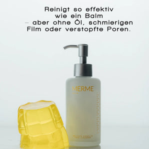 Eine Flasche MERME Berlin DELICATE DISSOLVE FACE CLEANSER mit einer Pumpe steht neben einem gelben, durchscheinenden Gel-Block. Der deutsche Text darüber betont die sanfte Reinigung ohne Öl, fettige Rückstände oder verstopfte Poren - ideal für empfindliche Haut.