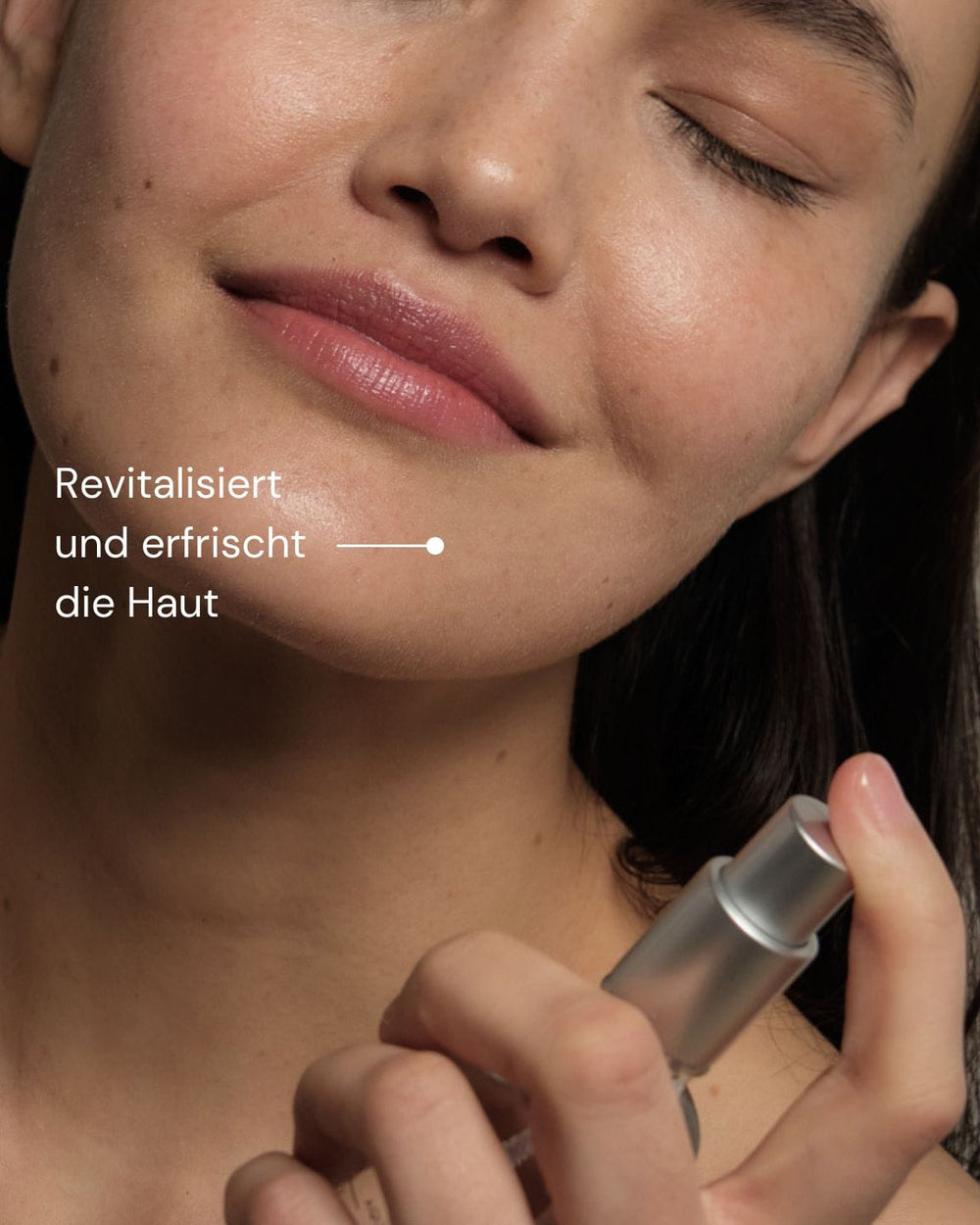 Eine Frau mit klarer Haut lächelt sanft, die Augen geschlossen, während sie MERME Berlin Fresh Dew Face Mist auf ihr Gesicht sprüht. Der deutsche Text lautet: "Revitalisiert und erfrischt die Haut für einen strahlenden Glow.