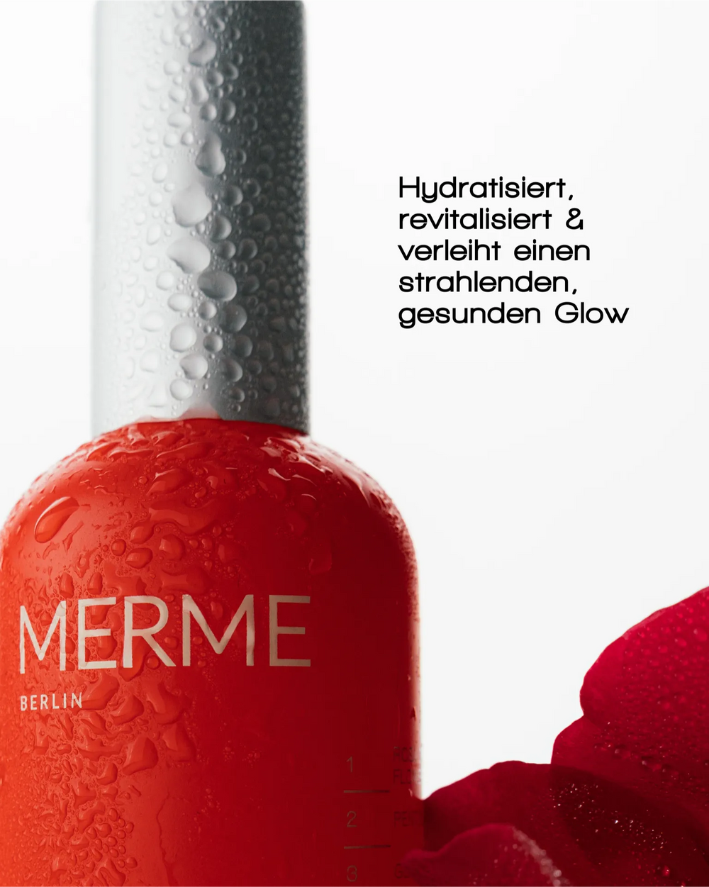 Nahaufnahme einer roten MERME Berlin FRESH DEW FACE MIST Flasche mit Wassertröpfchen, daneben ein rotes Blütenblatt. Der schwarze Text beschreibt es als feuchtigkeitsspendend und revitalisierend, um der Haut ein strahlendes, gesundes Aussehen zu verleihen.