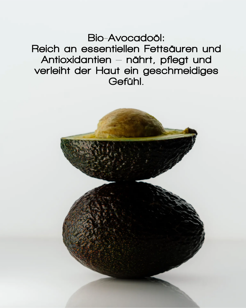 Eine ganze Avocado balanciert eine halbierte Avocado aus, die ihren Kern und ihr grünes Fruchtfleisch zeigt. Oben steht, dass MERME Berlin GENTLE BARRIER FACE CREAM mit Bio-Avocadoöl Feuchtigkeit spendet und die Hautbarriere stärkt.