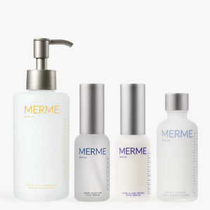 Vier minimalistische weiß-silberne Flakons aus dem "HYDRATE BY DAY, CLARIFY BY NIGHT"-Set von MERME Berlin - Gel-Reiniger, Feuchtigkeitsserum, Sprüh-/Tropfflasche und Feuchtigkeitscreme - sind nebeneinander angeordnet.