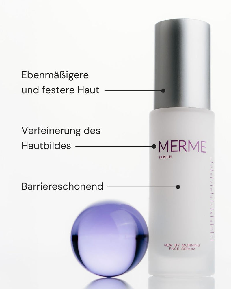 Ein gefrosteter Flakon des New by Morning Retinal Face Serum von MERME Berlin mit silbernem Verschluss steht neben einer lila Kugel. Der deutsche Text hebt die Vorteile hervor: gleichmäßige und straffe Haut, verfeinerte Textur und Barriereschutz.