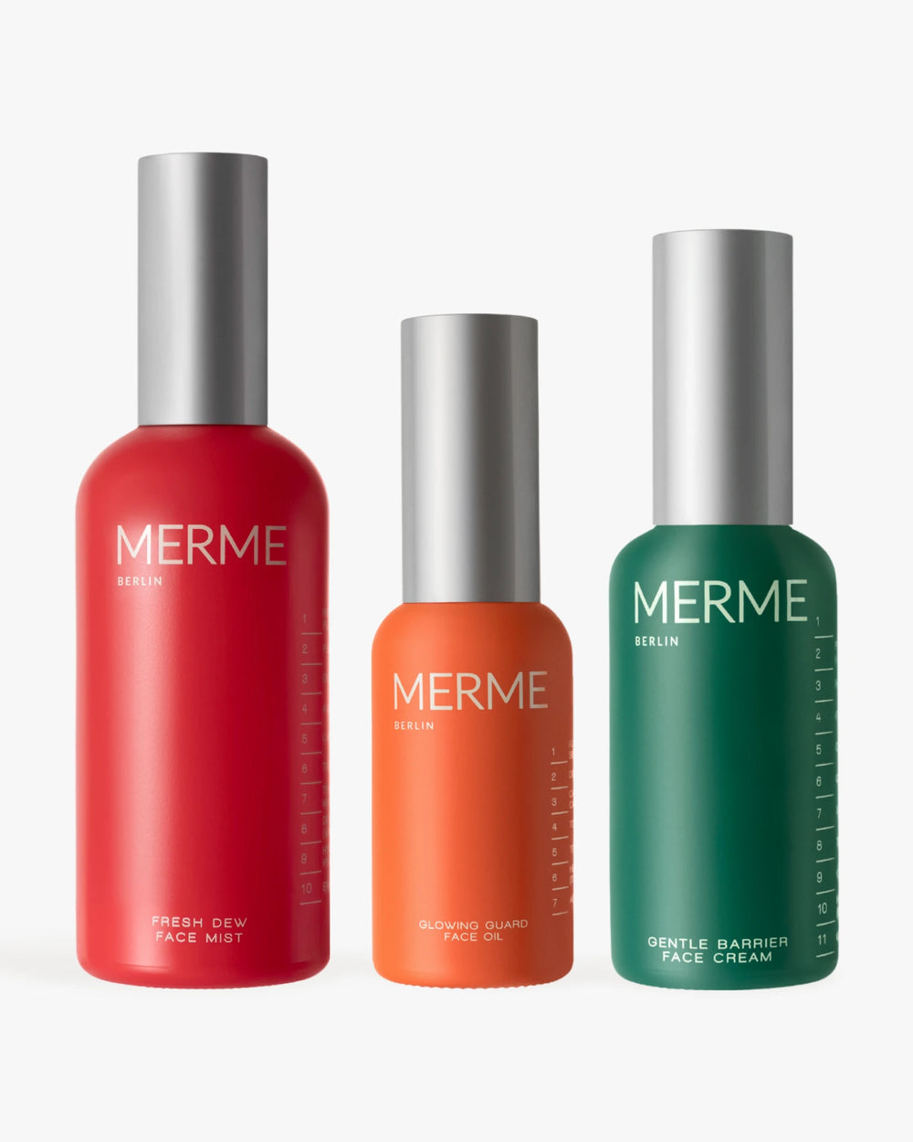 Drei MERME Berlin Hydrate. Verjüngen. Strahlen: Die organischen Produkte - roter Gesichtsnebel, oranges Gesichtsöl und grüne Feuchtigkeitscreme - stehen aufrecht mit silbernen Kappen auf weißem Hintergrund.
