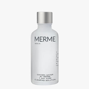 Eine klare, mattierte Flasche mit der Aufschrift "MERME Berlin" und einem silbernen Verschluss enthält OXYGEN WATER. Das minimalistische Design umfasst Messmarken und schwarzen Text auf einem weißen Etikett.