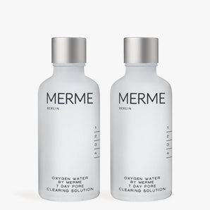 Zwei mattierte Flaschen mit der Aufschrift "MERME Berlin OXYGEN WATER PORE CLEARING SOLUTION - 2 WOCHEN" stehen nebeneinander und sind mit einem minimalistischen schwarzen Text versehen. Diese Sprays nutzen die Sauerstoff-Microbubble-Technologie für eine effektive Hautpflege.
