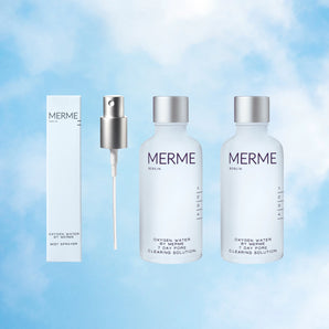 Das OXYGEN WATER BY MERME 2-WOCHEN-SET von MERME Berlin, bestehend aus zwei Flaschen, einem silbernen Zerstäuber und einer weißen Schachtel, wird vor einem himmelblauen Wolkenhintergrund gezeigt, der die Sauerstoff-Microbubble-Technologie hervorhebt.