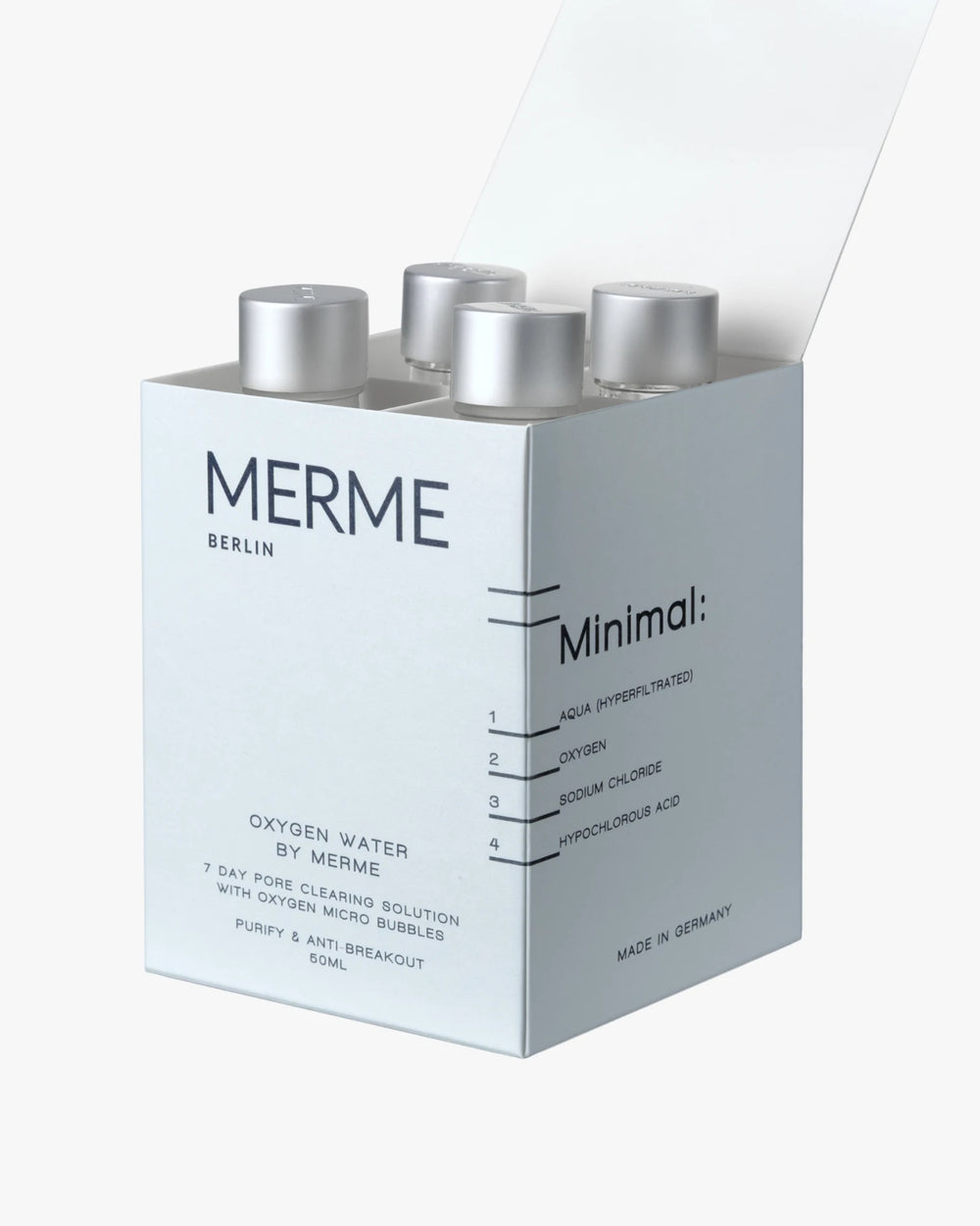 In einer teilweise geöffneten weißen Schachtel mit der Aufschrift "MERME Berlin OXYGEN WATER 4-WOCHEN-SET" befinden sich vier Flaschen. Die minimalistische Verpackung listet nur wenige Inhaltsstoffe auf und behauptet, die Haut zu reinigen und Hautausbrüche zu verhindern.