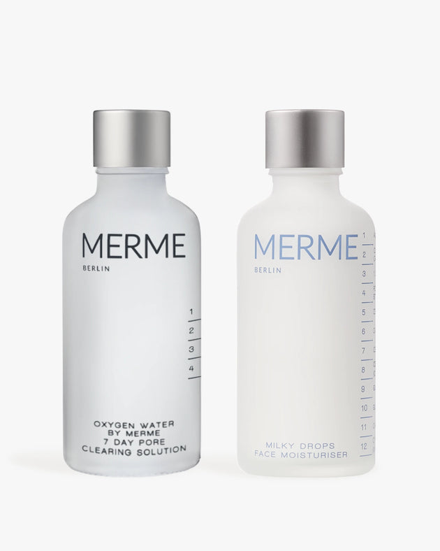 Zwei Flaschen von MERME Berlin: Links-CLEAR & SOOTHE mit einer glänzenden Silberkappe; rechts-Milky Drops Face Moisturiser mit einer matten Silberkappe.