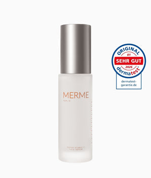 Ein Milchglasflakon von MERME Berlin Super Stable C Face Serum mit einer Metallkappe steht neben einem kreisförmigen Dermatest "Sehr Gut" Qualitätssiegel 2026.