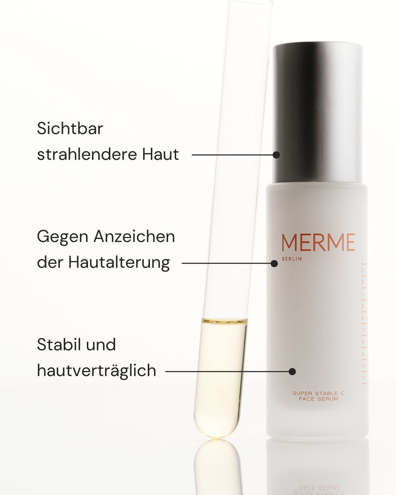 Eine Flasche MERME Berlin Super Stable C Face Serum steht neben einem Reagenzglas mit blassgelber Flüssigkeit. Der deutsche Text hebt die strahlende Haut, die Anti-Aging-Wirkung und die stabile, hautverträgliche Wirkung hervor.